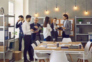 Wall Mural - Office colleagues talking at work discussing project strategic plan sharing idea. Group of business people standing n bright room and speaking. Workflow process, corporate member and meeting concept