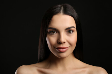 Poster - Portrait of happy young woman with beautiful black hair and charming smile on dark background