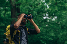 A Hiker Man Walking In The Forest Using Binoculars