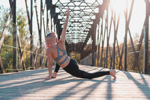 Unrecognizable Woman Practicing Yoga With Raised Arm On Bridge