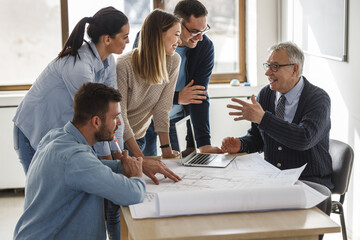 Wall Mural - College professor examining blueprint with group of his students.	