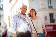 © mimagephotos - smiling older couple standing outside in city