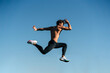 © ADDICTIVE STOCK - Fast runner jumping during workout under blue sky