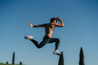 © ADDICTIVE STOCK - Fast runner jumping during workout under blue sky