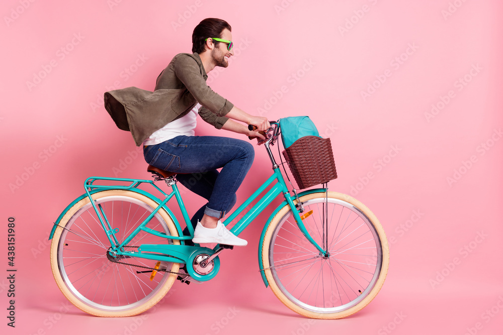 Full length body size profile side view of attractive cheerful guy riding bike isolated over pink pastel color background - obrazy, fototapety, plakaty 
