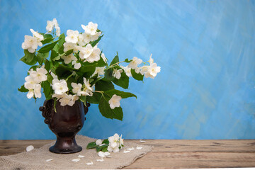 Poster - A bouquet of jasmine in a brown vase on a blue background