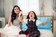 © chokniti - Happy loving family time. Mother and daughter are doing hair and having fun. Mother playing with kid on the bed in the bedroom, doing hair style, asian family concept.