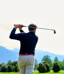 Wall Mural - Golfer on the professional golf course. Golfer with golf club hitting the ball for the perfect shot.