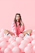 © GVS - Young trendy surprised woman with pink balloons on pink pastel background