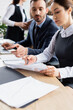 © LIGHTFIELD STUDIOS - Businesswoman pointing at document near colleague on blurred background