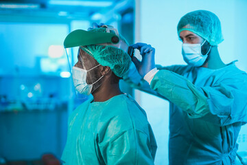 multiracial doctors preparing and getting dressed to work inside hospital during coronavirus pandemi