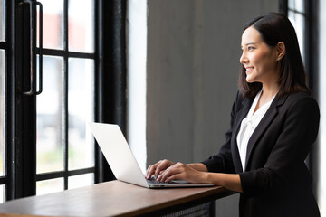 businesswoman working with laptop computer and looking at window in office