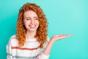 Photo of funky ginger wavy hair young lady hold hand empty space wear sweater isolated on teal color background