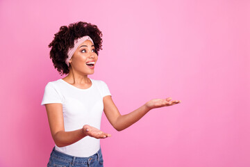 Poster - Photo portrait of curly girl looking up holding hands looking blank space isolated on pastel pink color background