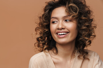 Young curly hispanic woman smiling and looking aside