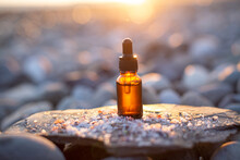 CDB Oil Bottle Standing On A Rock With Scattered Himalayan Salt Against The Background Of A Sunset At The Sea