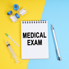 A syringe, ampoules and a notebook with the inscription - Medical Exam