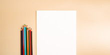 A Blank White Sheet And Colored Pencils For Drawing On A Plain Textured Background With Space For Copying And Lettering.