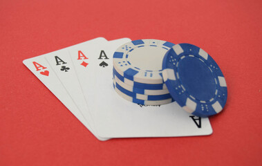 A winning hand of four aces and poker chips on a red background.