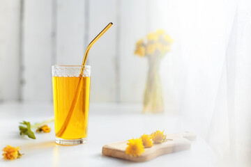 Dandelion honey juice in a glass with a metal tube and fresh flowers