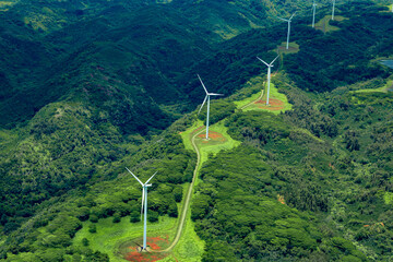 aerial photo of white windmills in a line on green land leading off into the horizon.
