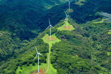 Aerial Photo Of White Windmills In A Line On Green Land Leading Off Into The Horizon.