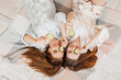 © Daria Lukoiko - Two girls make homemade face and hair beauty masks. Cucumbers for the freshness of the skin around the eyes. Women take care of youthful skin. Girlfriends laugh at home lying on the floor on pillows.