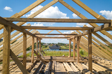 Wall Mural - Aerial view of unfinished house with wooden roof frame structure under construction.