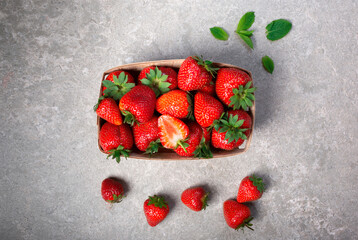 Basket of fresh strawberries on a gray stone background