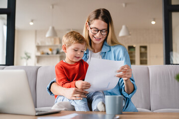 little small toddler kid child son helping her busy young mother with freelance remote work holding 