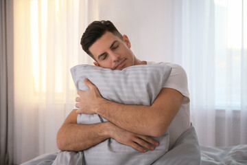 Canvas Print - Man hugging pillow on bed with grey linens at home