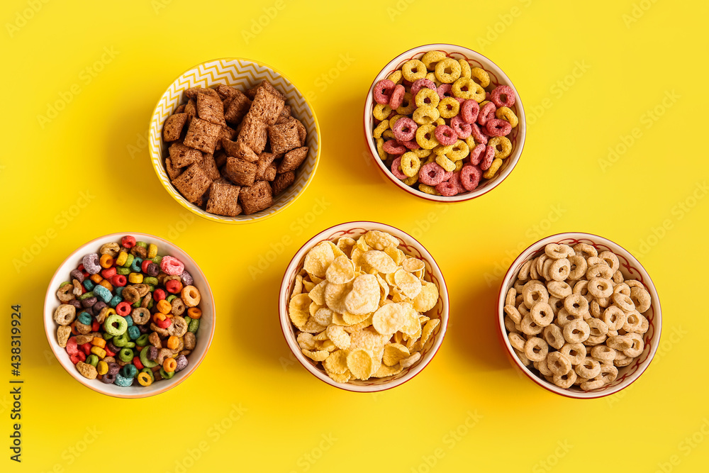 Bowls with different cereals on color background