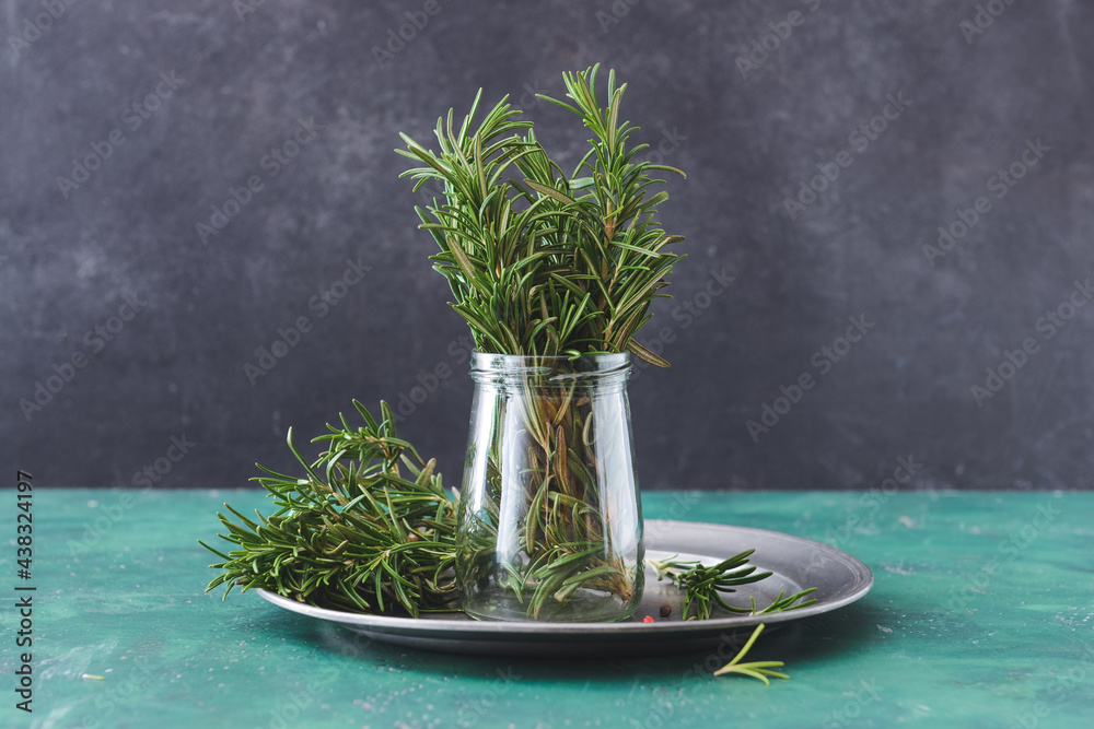 Jar with fresh rosemary on table against dark background