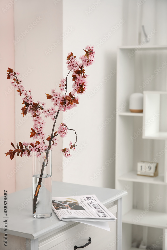 Vase with beautiful blossoming branches in room