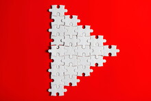 White Jigsaw Puzzle Resemble Small  Triangle Or Play Logo Icon Button On Plain Red Background  