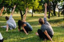 A Group Of People Do Yoga In The Park At Sunset. Healthy Lifestyle, Meditation And Wellness