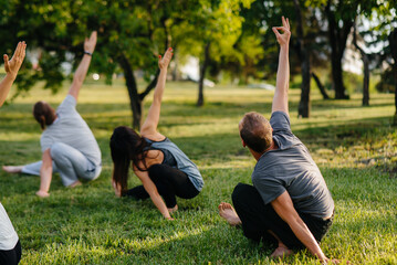 A group of people do yoga in the Park at sunset. Healthy lifestyle, meditation and Wellness