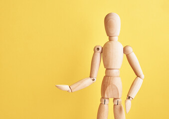 Wall Mural - Wooden doll with gesture on yellow background. Mannequin shows gesture. Figure of wooden human with copy space