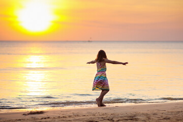 Child playing on ocean beach. Kid at sunset sea.