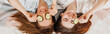 © Daria Lukoiko - Two girls make homemade face and hair beauty masks. Cucumbers for the freshness of the skin around the eyes. Women take care of youthful skin. Girlfriends laugh at home lying on the floor on pillows.