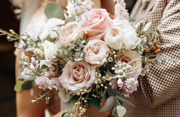 Bride and groom on wedding day hug and show love with a wedding bouquet of rose flowers