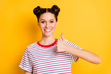 Wall Mural - Photo of sweet shiny young lady wear striped t-shirt smiling showing thumb up isolated yellow color background