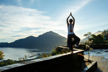 Sticker - Woman doing yoga at dawn near a volcano on the island of Bali