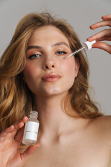 Poster - Half-naked blonde woman looking at camera and applying face serum