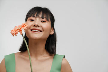 Wall Mural - Young asian woman smiling while posing with gerbera flower