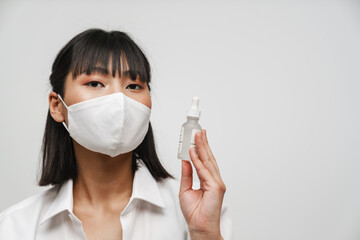 Wall Mural - Young asian woman in face mask showing facial serum