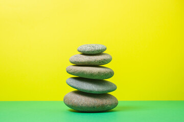 Flat stones stacked on top of each other on a colored background. The concept of calmness and balance
