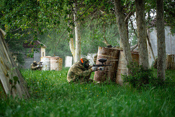 People in uniforms with guns play paintball