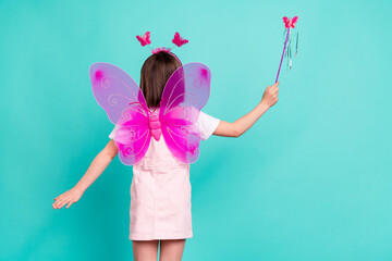 Photo of sweet carefree schoolgirl dressed pink overall wings holding fairy wand isolated turquoise color background