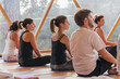 © ADDICTIVE STOCK - Attentive people sitting on yoga mat before trainers in decorated room